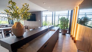 A modern kitchen with a large island, a vase with greenery, and a view of the city through large windows. - High-floor apartment with city views (Guadalajara)