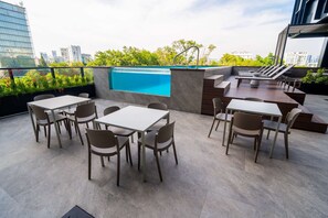 A rooftop terrace with a pool, seating area, and city views.