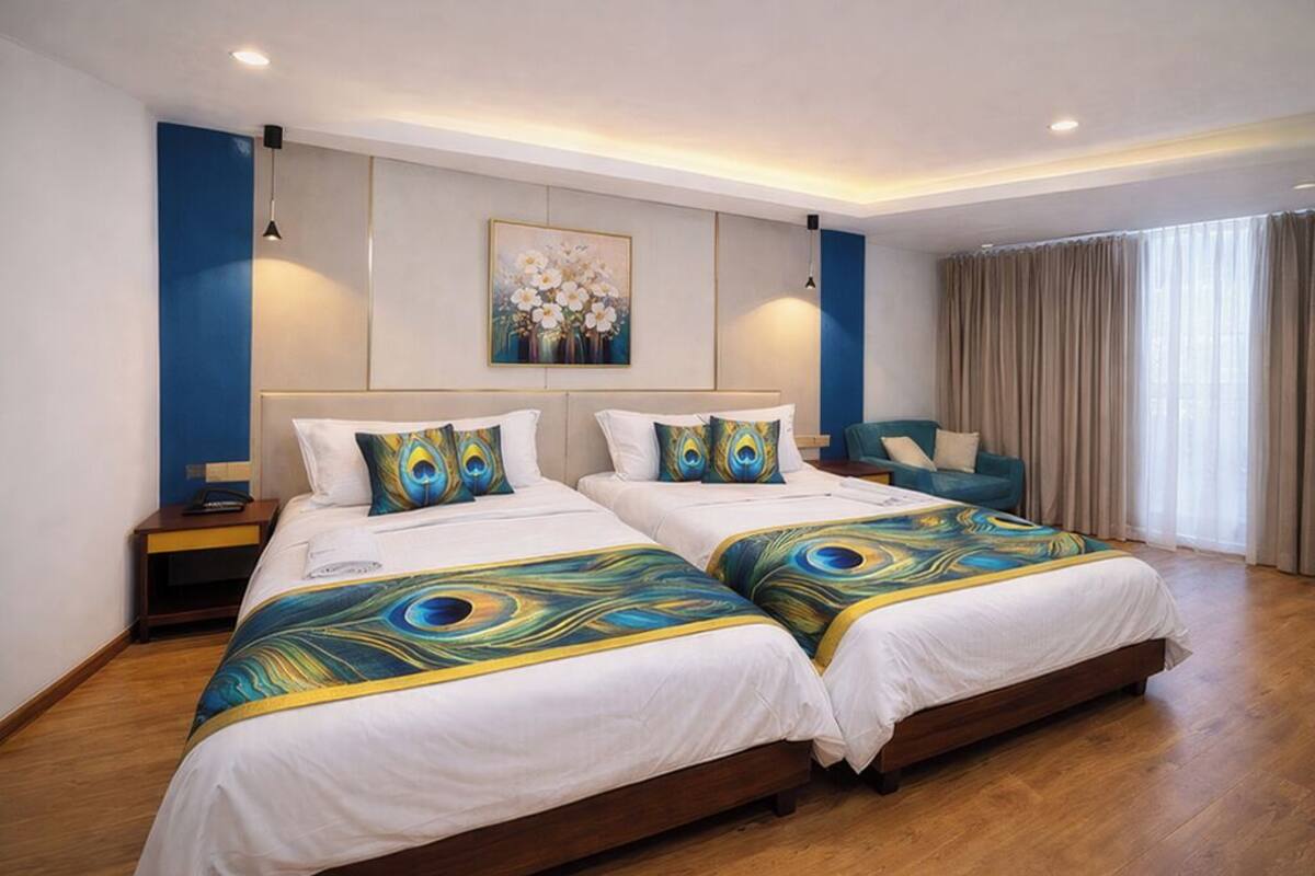 Une chambre avec un grand lit, deux lits simples, une table de chevet, une chaise et un tableau au mur.