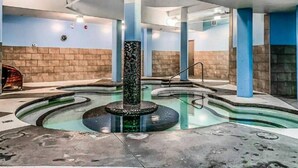 Piscina com uma fonte central, rodeada por pilares azuis e um chão revestido de azulejos.