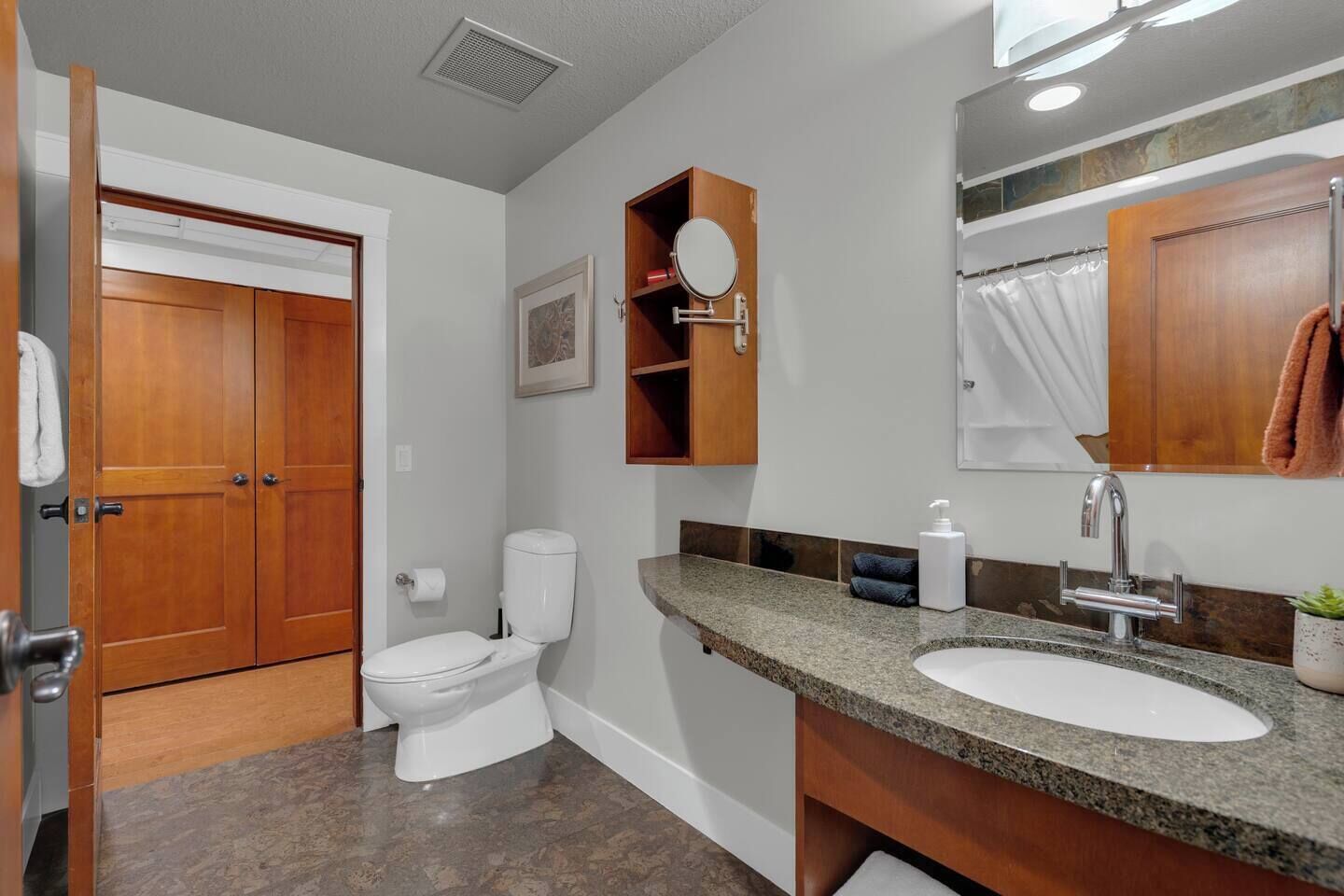 A bathroom with a toilet, sink, and wooden cabinets.