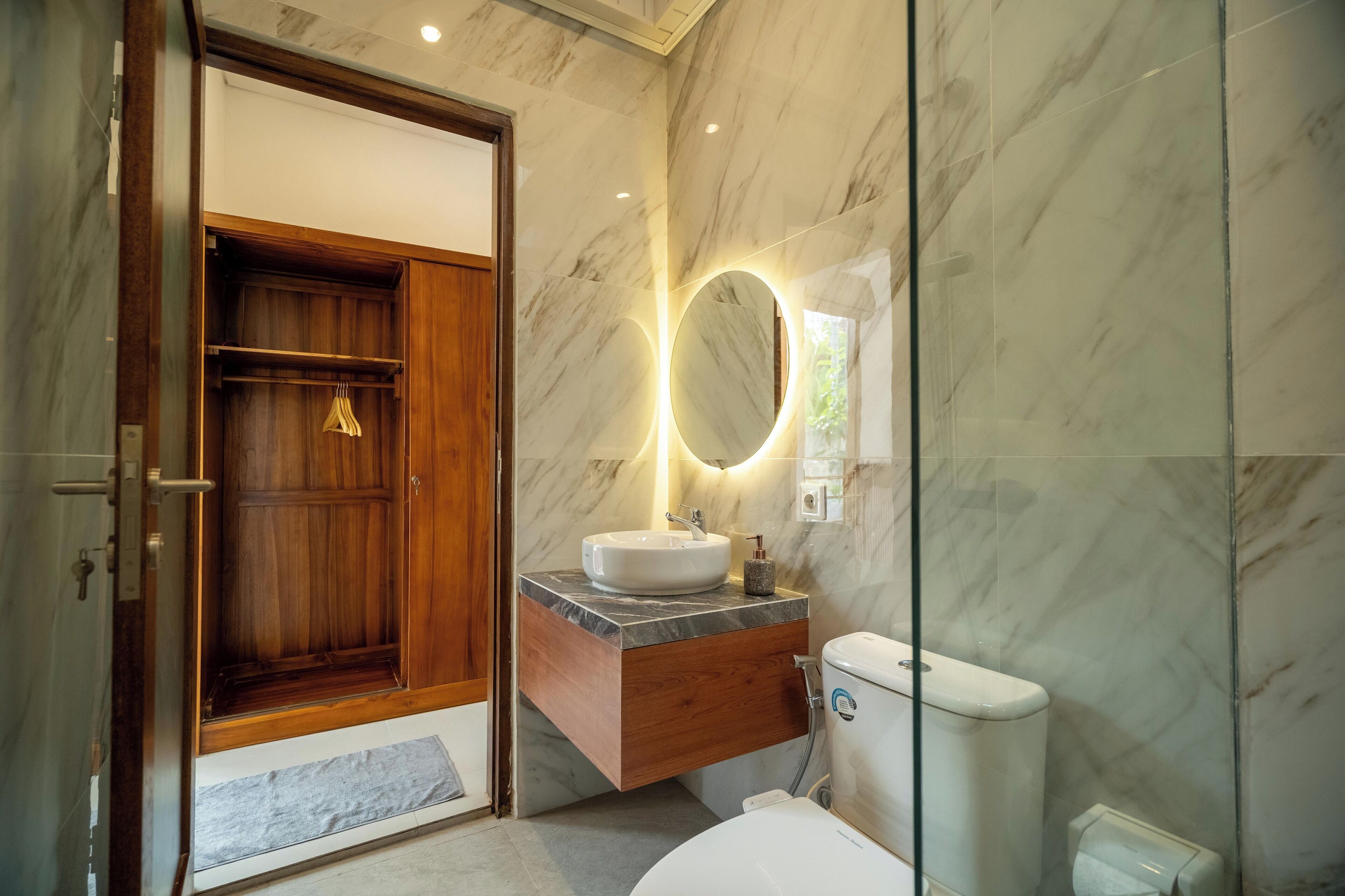 A modern bathroom with a wooden vanity, a marble sink, and a glass shower enclosure.