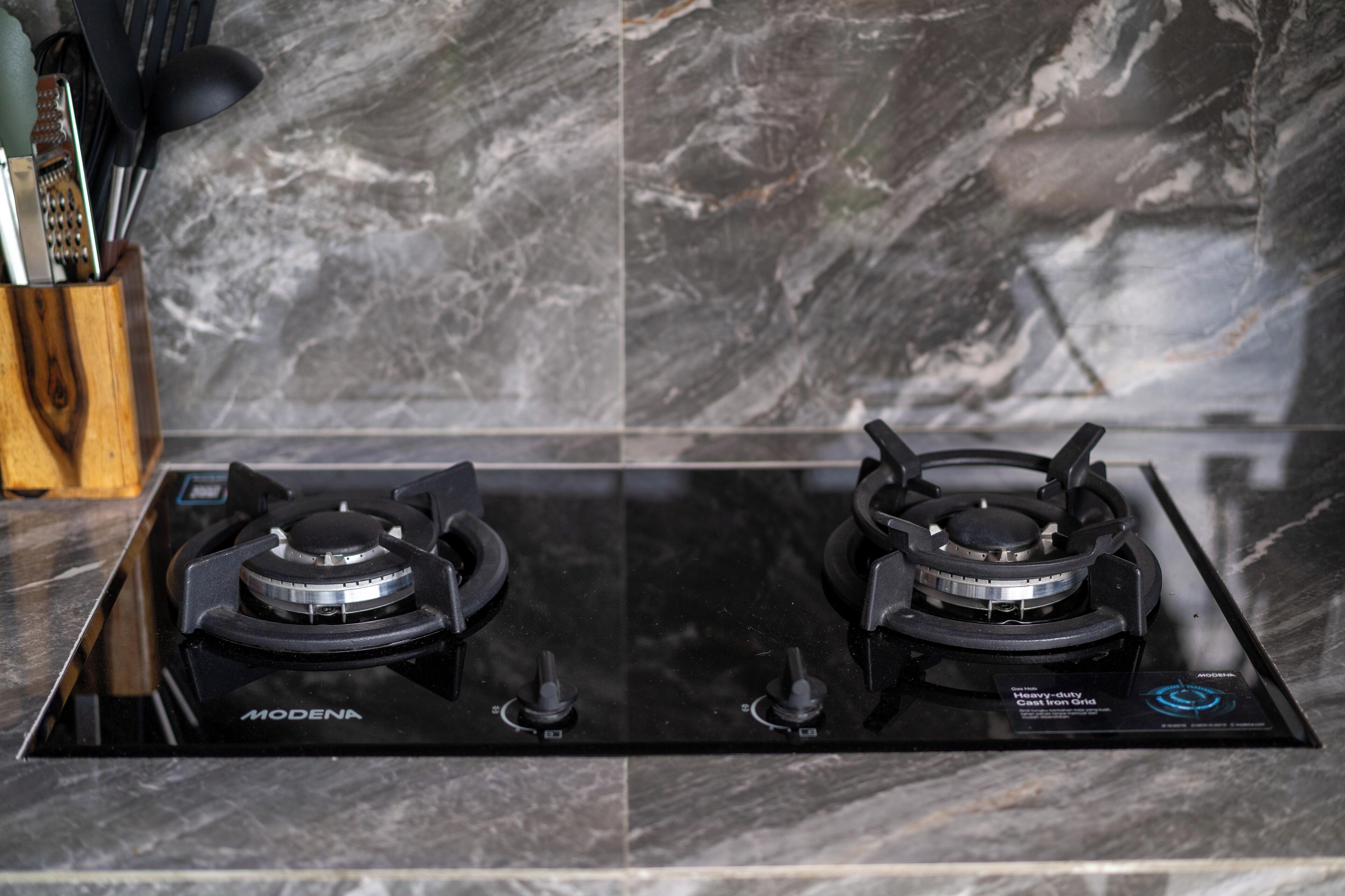 A black gas stove with two burners and a control panel, set on a marble countertop.