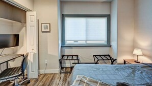 A bedroom with a bed, a desk, a chair, a TV, and a window. - Downtown 2BD 1BA - 2 Blocks to Main/River #187 (Buena Vista)
