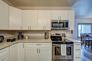 A modern kitchen with white cabinets, a stainless steel microwave, a coffee maker, and a stove. - Downtown 2BD 1BA - 2 Blocks to Main/River #187 (Buena Vista)