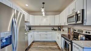 A modern kitchen with stainless steel appliances, white cabinetry, and a wooden floor. - Downtown 2BD 1BA - 2 Blocks to Main/River #187 (Buena Vista)
