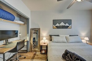 Ein Schlafzimmer mit Bett, Schreibtisch, Stuhl, Fernseher und einem Bild an der Wand.