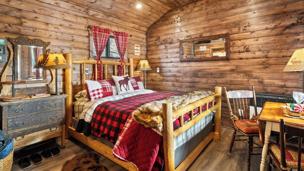 Een houten kamer met een bed, een dressoir, een tafel en een stoel.