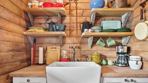 Een keuken met houten planken, een spoelbak en divers keukengerei.