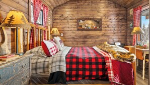 Een knus slaapkamer in een blokhut, met een bed, twee lampen, een dressoir en een spiegel.