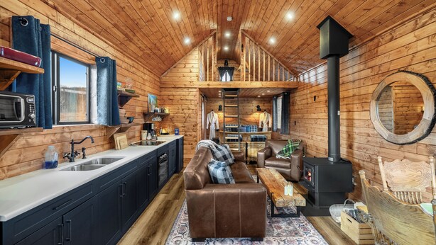 Een gezellig houten blokhut interieur met een keuken, eethoek en een open haard.