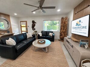 Ein modernes Wohnzimmer mit einer schwarzen Ledersofa, einem runden Couchtisch und einer Wand mit Holzvertäfelung.