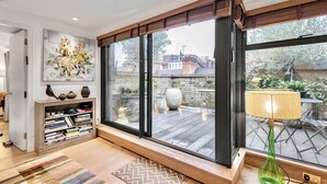 A modern living room with a large sliding glass door leading to an outdoor patio. - The Mayfair Penthouse Private Elevator Large Rooftop Terrace Central AC (London)