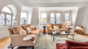 A spacious loft apartment with high ceilings, large windows offering city views, a modern living area with sofas and a coffee table, and a red accent chair. - The Mayfair Penthouse Private Elevator Large Rooftop Terrace Central AC (London)