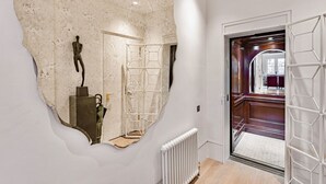 A hallway with a large mirror, a radiator, and a door leading to another room. - The Mayfair Penthouse Private Elevator Large Rooftop Terrace Central AC (London)