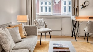 A modern living room with a sofa, armchair, coffee table, and a desk with a lamp. - Mayfair 2-bed With Private Parking Near Buckingham Palace Green Park (London)
