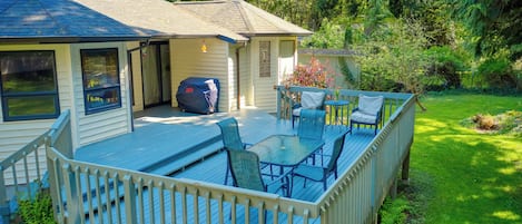 Una terraza con mobiliario exterior, una parrilla cubierta y una casa con porche.