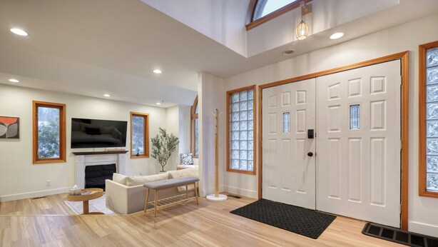 Un salon spacieux avec une cheminée, un canapé, une table basse et un téléviseur fixé au mur.