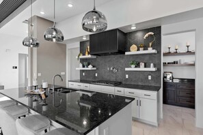 A modern kitchen with a central island, black countertops, and a herringbone-patterned backsplash.