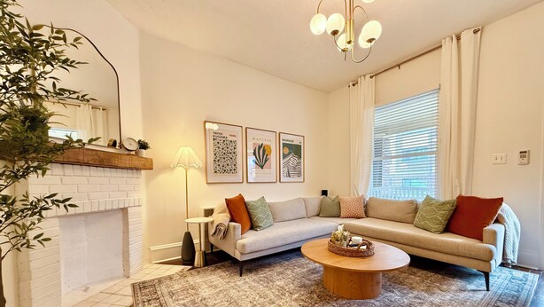 A living room with a fireplace, a sofa, a coffee table, and a floor lamp. - Hot tub - Mass Ave - Sleeps 9 - Free parking (Indianapolis)