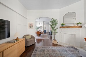 Ein modernes Wohnzimmer mit Flachbildfernseher, einer Couch, einem Couchtisch und einem Kamin.