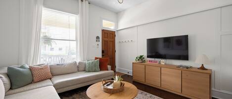 Una sala de estar moderna con un sofá, una mesa de centro, un televisor y un mueble de madera.