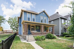A two-story house with a front porch, a brick column, and a small front yard.