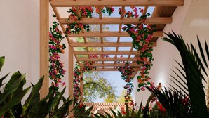 A covered walkway with a wooden pergola, surrounded by lush tropical plants and flowers. - Villa Meru (Seminyak)