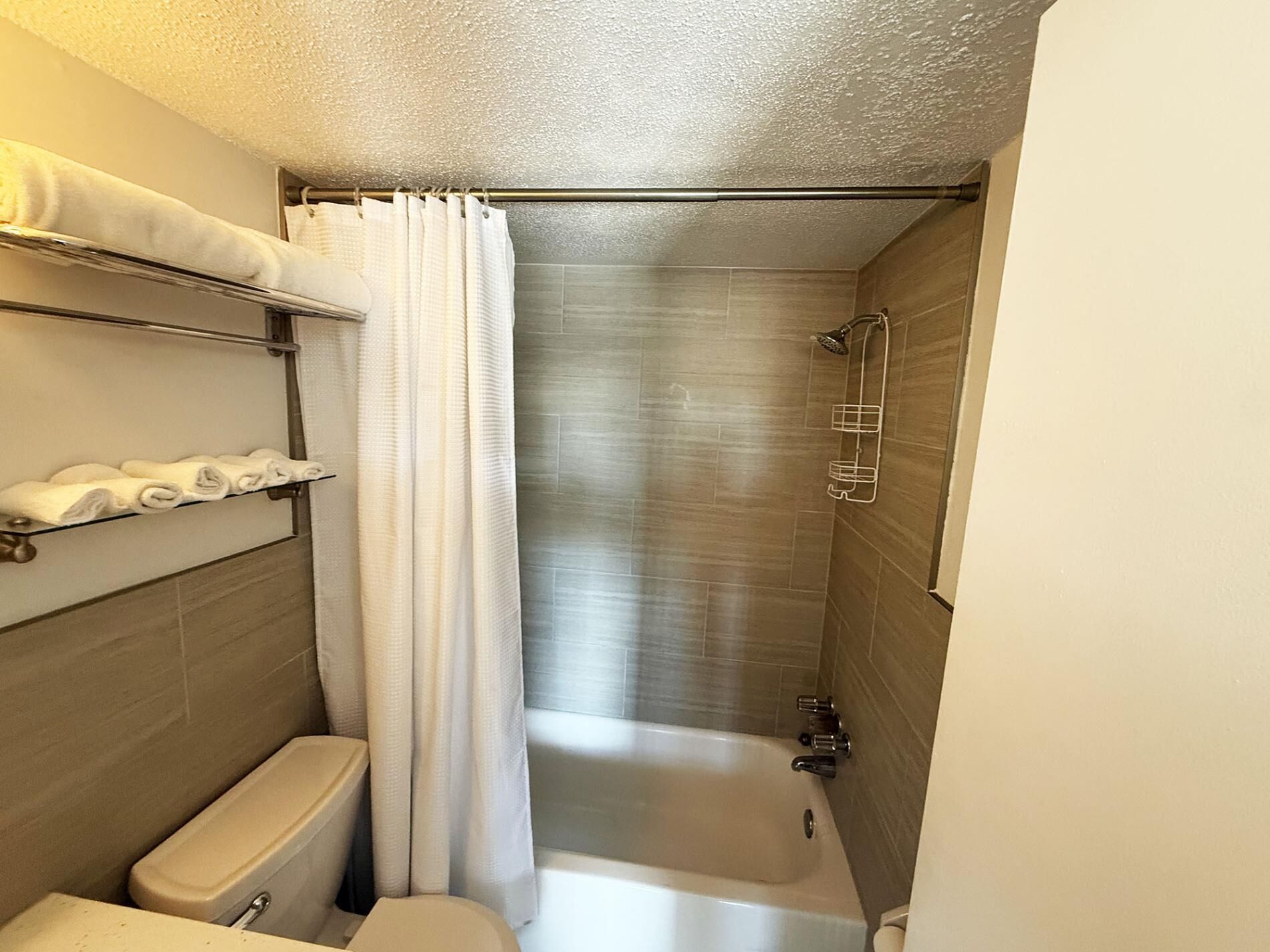 Une salle de bain de taille réduite, comprenant des toilettes, une douche et une baignoire.