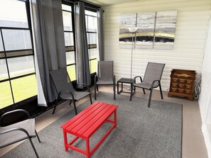 Ein Zimmer mit einer roten Bank, grauen Stühlen, einem kleinen Tisch und einem Bild an der Wand.
