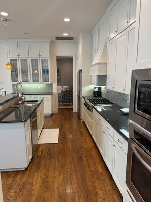 A modern kitchen with white cabinets, a stainless steel refrigerator, and a black countertop.