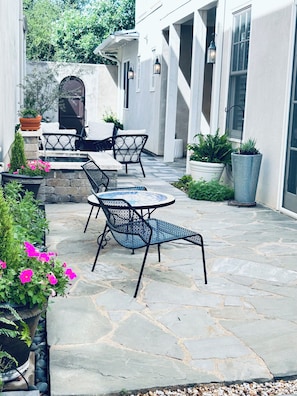 A patio area with stone flooring, outdoor furniture, and potted plants.