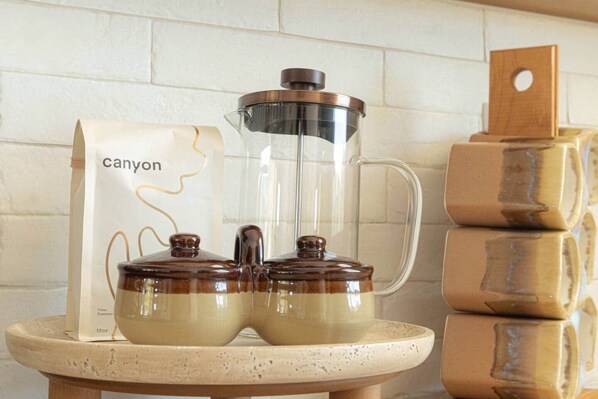 A kitchen setting with a coffee maker, a bag labeled 'canyon,' and stacked jars on a countertop. - Golden Hour Desert Retreat • Joshua Tree National Park (Twentynine Palms)