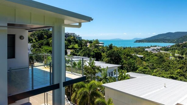 A modern house with a balcony overlooking a coastal landscape, including a view of the sea and hills. - Summit Apartments Airlie Beach (Airlie Beach)