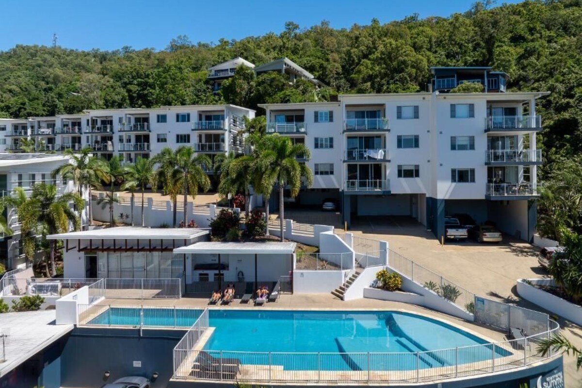Un resort con varias edificaciones blancas, una piscina y palmeras.