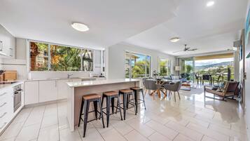A modern kitchen with a large island, bar stools, and a dining area with a view.
