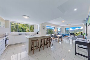 Une cuisine moderne dotée d’un grand îlot central, de tabourets de bar et d’un coin repas offrant une vue agréable.