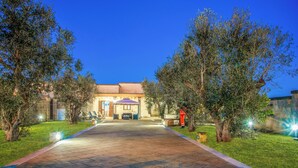 A pathway leading to a building with a covered area, surrounded by trees and illuminated by lights. - Villa Gloria with Garden near the Sea, Melendugno, Italy (Melendugno)