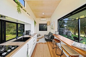 Una cocina moderna con un ventanal grande, estufa empotrada y un rincón comedor con banco.