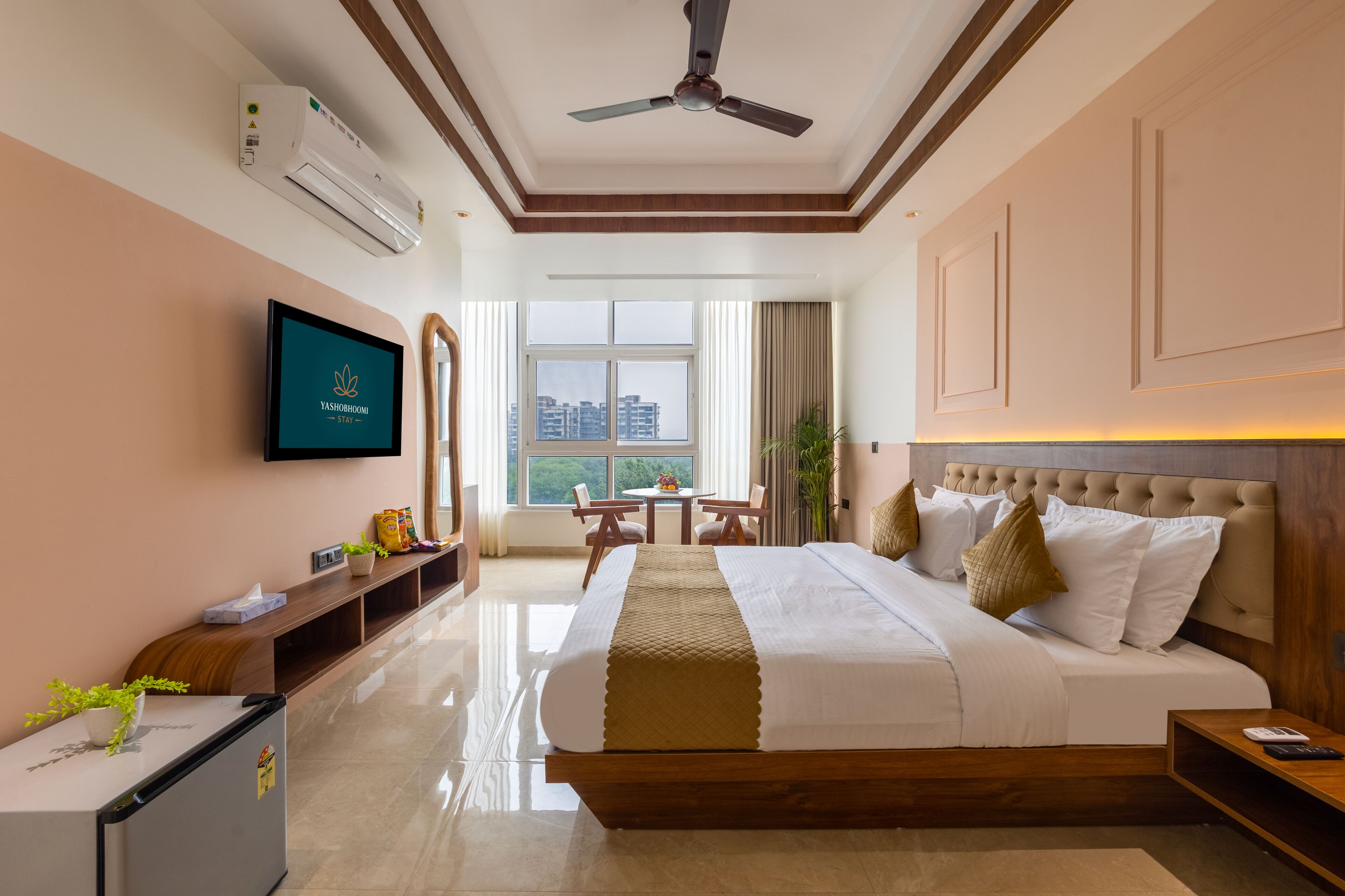 A hotel room with a bed, a television, a desk, and a window with a city view.
