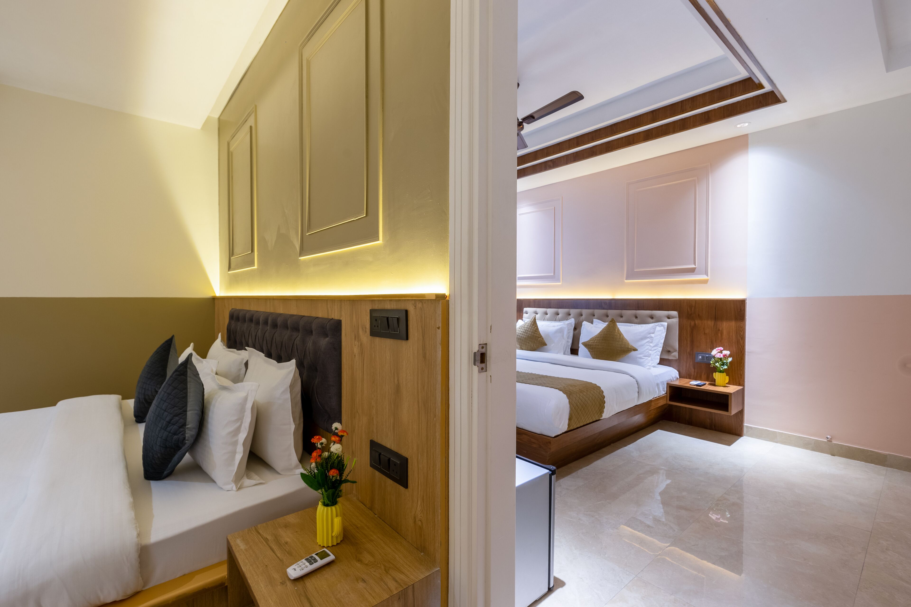 A hotel room with a bed, bedside table, and a view of the adjacent room.