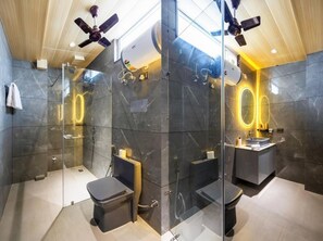 Ein modernes Badezimmer mit einer begehbaren Glasdusche, einem Waschtisch mit Spiegel und einem Deckenventilator.