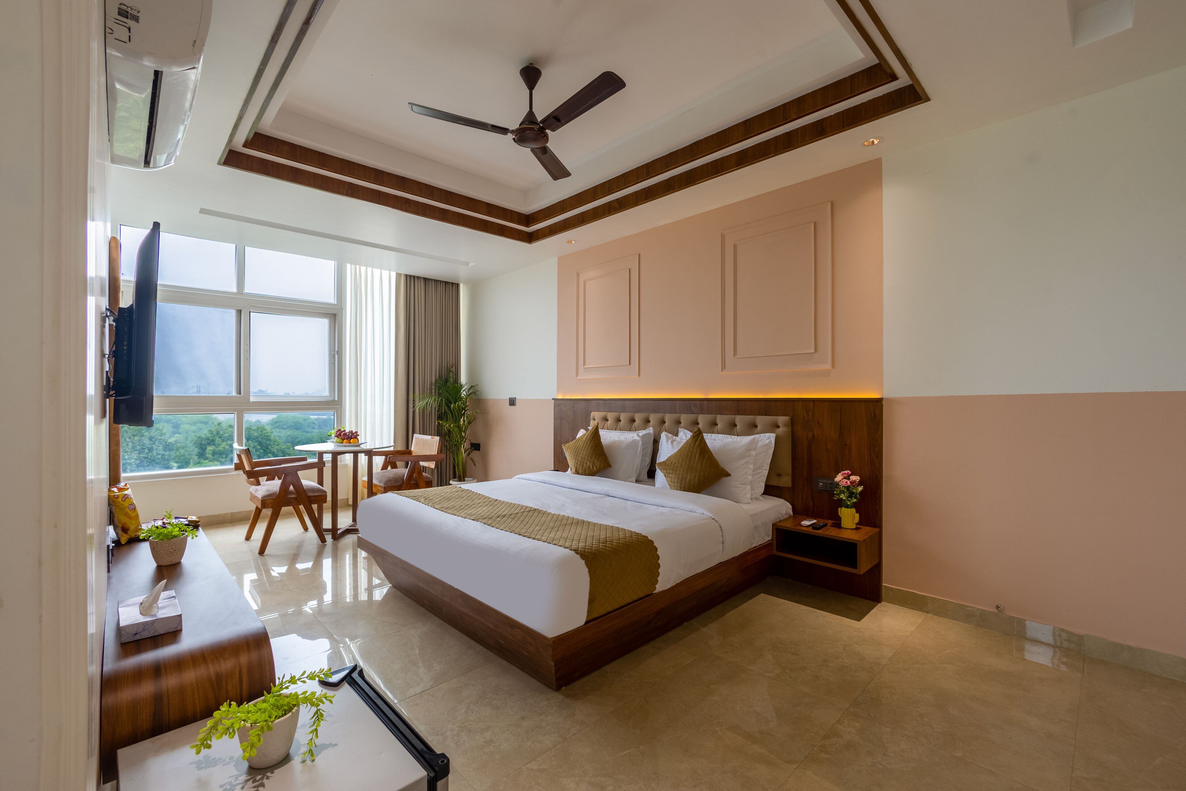 A hotel room with a bed, bedside table, nightstand, and a window with curtains.
