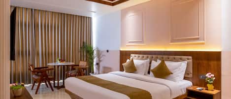 Habitación de hotel moderna con una cama grande, un escritorio, una silla, un ventilador de techo y una ventana con cortinas.
