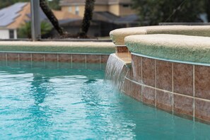 En swimmingpool med et vandfald og flisebeklædte vægge.