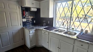 A kitchen with white cabinets, a black countertop, and a window with a view of trees.