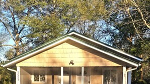 A single-story building with a covered porch, a number '1662' on the side, and a small table and chairs in front.