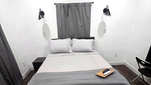 A neatly arranged bedroom with a large bed, two bedside tables, a chair, and a window with curtains.
