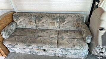 Un canapé de style vintage, orné d’un motif camouflage, placé à l’intérieur d’un véhicule.