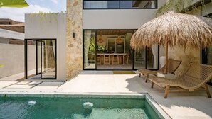 A modern house with a pool, outdoor seating, and a dining area.